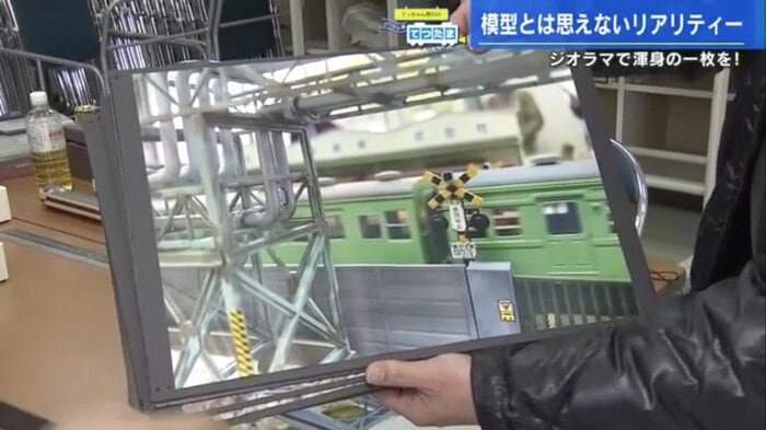工場の間を走り抜ける鉄道模型の写真