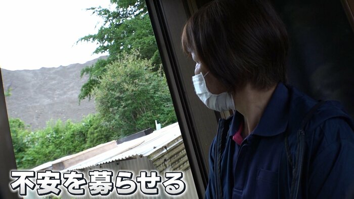雨が降る中、不安そうに盛り土を見る児山さん