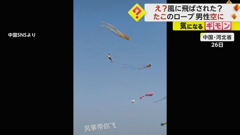 ビル数階分の高さまで上がっている男性