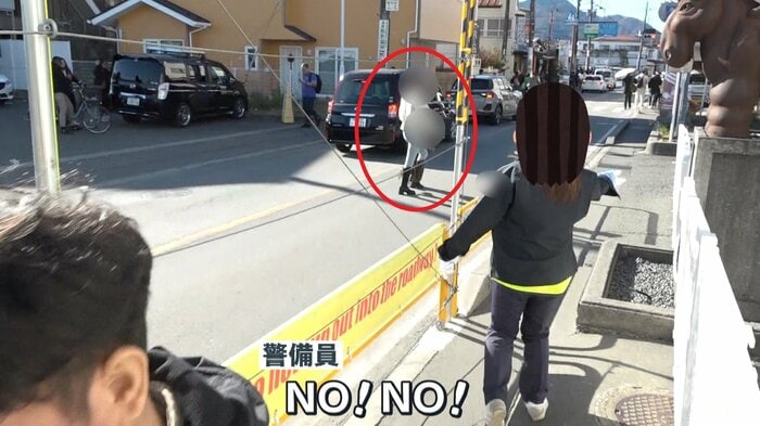 車道を横断する親子を制止する警備員
