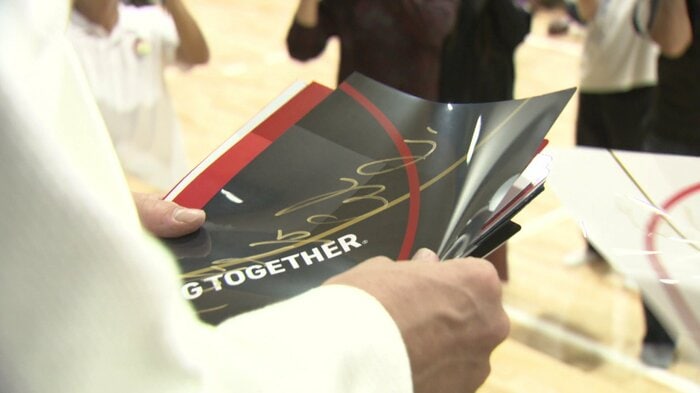 自らが書いたサイン入りのグッズを後輩に一つ一つ渡す永瀬選手
