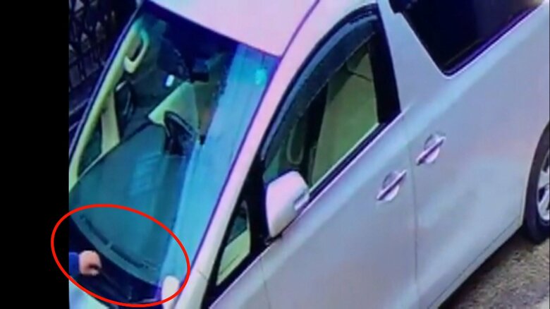 止めてあった車のワイパーに手をかける(別カメラ)