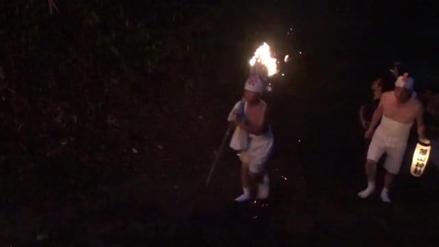 重い松明を担ぎぬかるんだ山道を登る