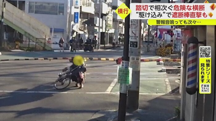 下りきった遮断棒の下をくぐって通ろうとした自転車の人