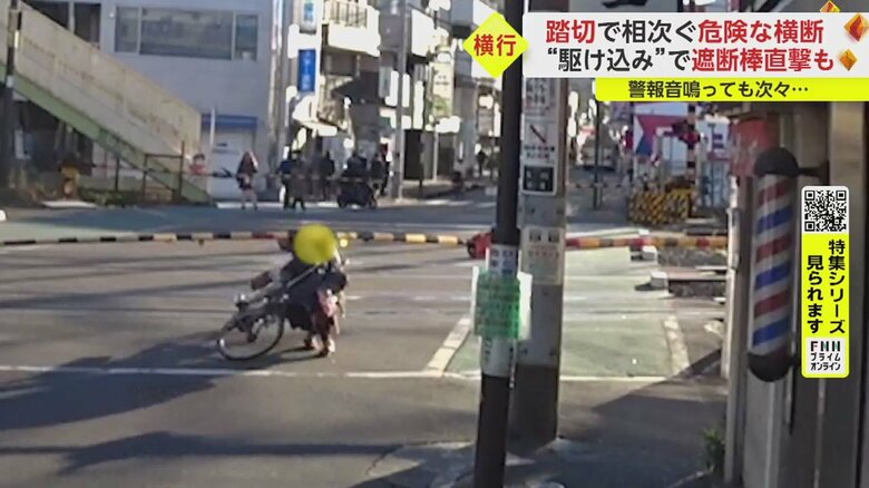 下りきった遮断棒の下をくぐって通ろうとした自転車の人
