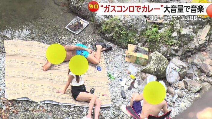 くつろぐ男女の横には焦げた段ボールが…