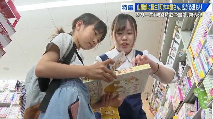 1人で来店した小学生と一緒に本を探す原田店長