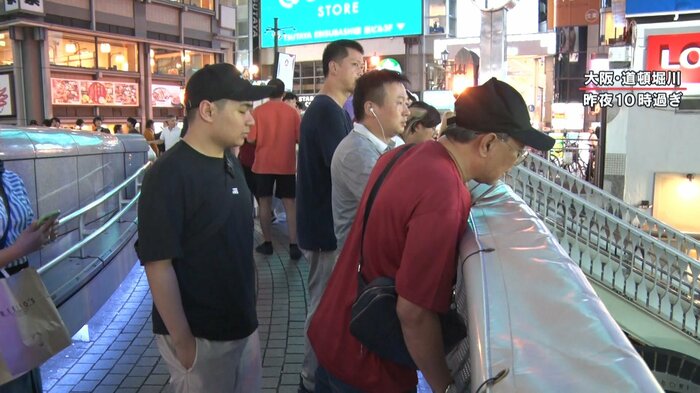 心配そうに橋から川をのぞき込む人々
