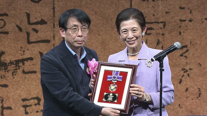 慈行会会長の金愚さんの代理人にメダルを手渡された