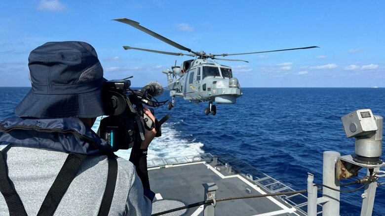 甲板に着陸するヘリコプターを撮影する水長卓朗カメラマン