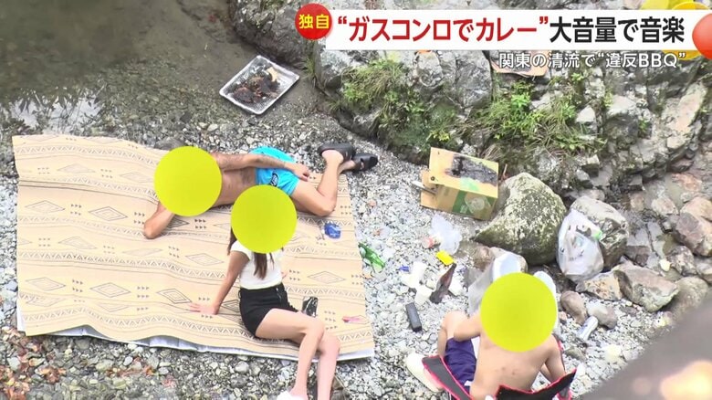 くつろぐ男女の横には焦げた段ボールが…