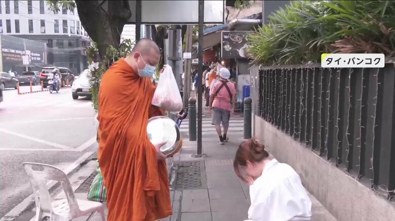 托鉢（たくはつ）する僧侶と手を合わせる人