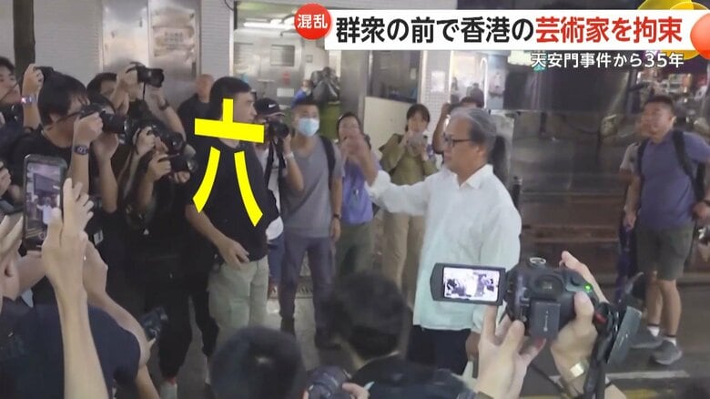 手で空を切るように漢数字の「六」を書く芸術家の男性