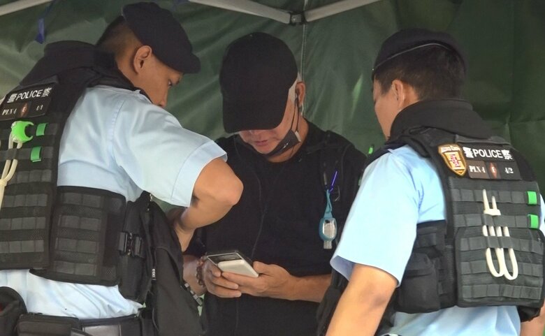 警察官にスマホの写真をチェックされる男性（6月4日）