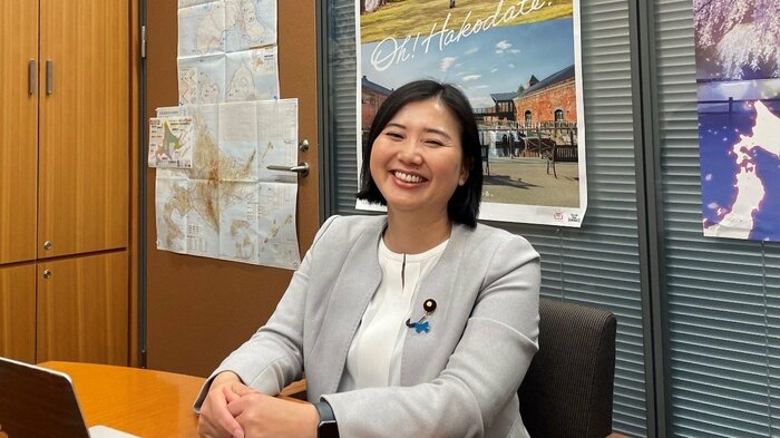 笑顔で取材に応じる向山淳議員　背後には地元北海道のポスター