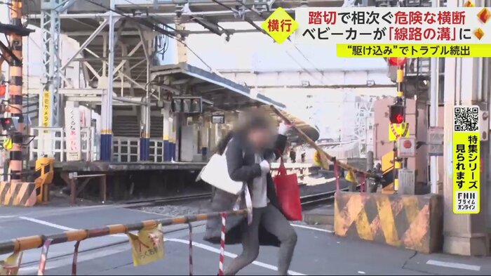 遮断棒を手で持ち上げて踏切から出る人