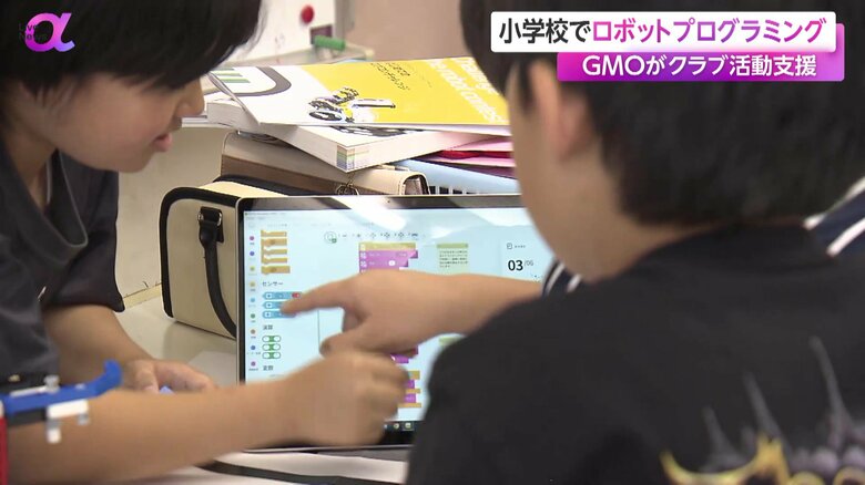 タブレットでプログラムを組んでロボットを操作する児童