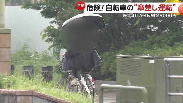 傘を差しながら自転車を運転している人物（9日、静岡市）