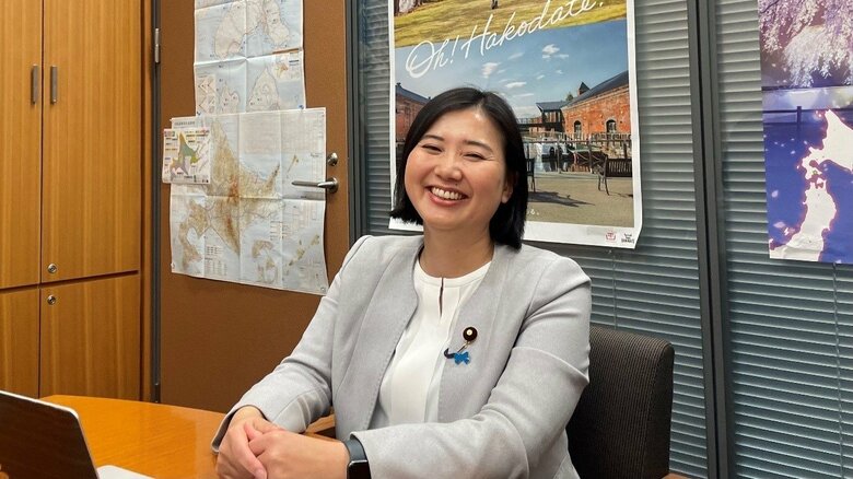 笑顔で取材に応じる向山淳議員　背後には地元北海道のポスター