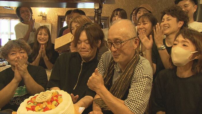 閉店前、記念撮影で常連客と家族に囲まれる久保田さん(8月24日)
