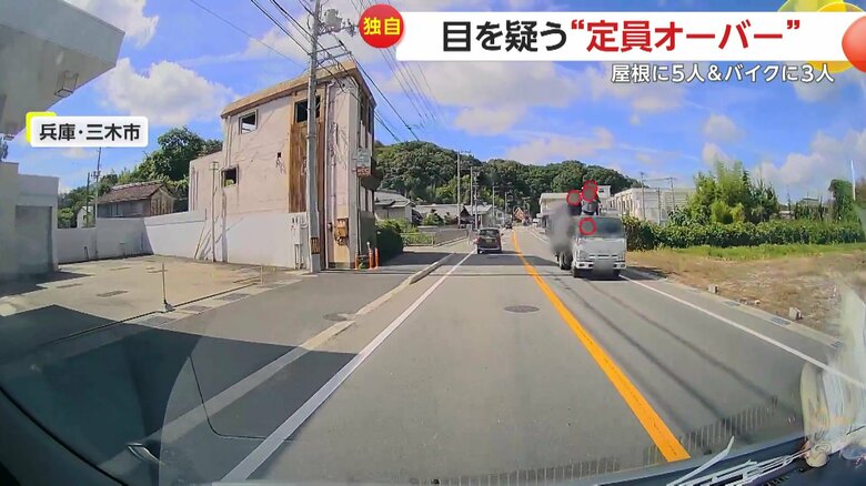 屋根に複数人が乗ったまま対向車線を走行するゴミ収集車