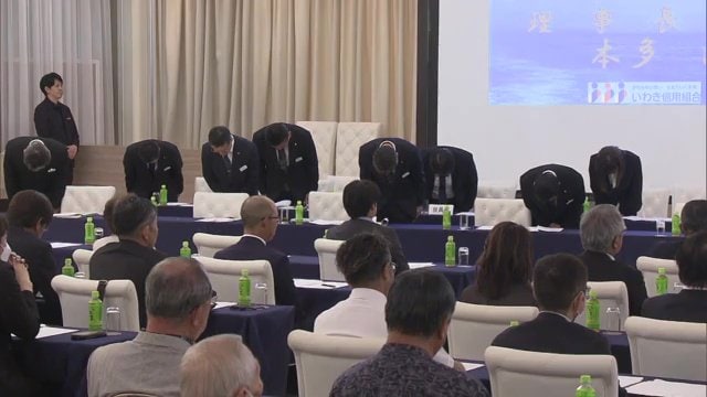 総代会で頭をさげる役員