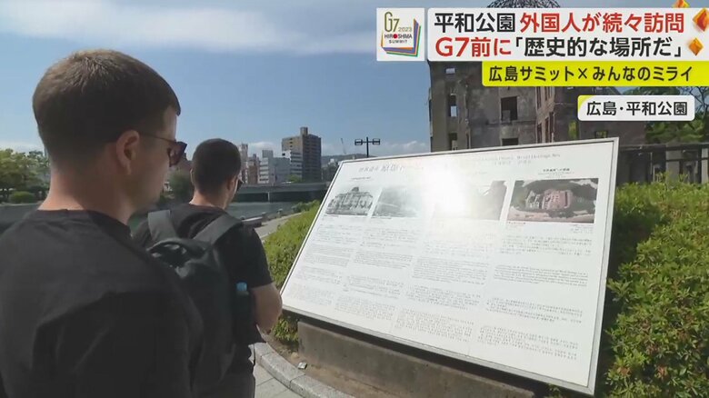 原爆ドームに関する説明を読む外国人観光客たち