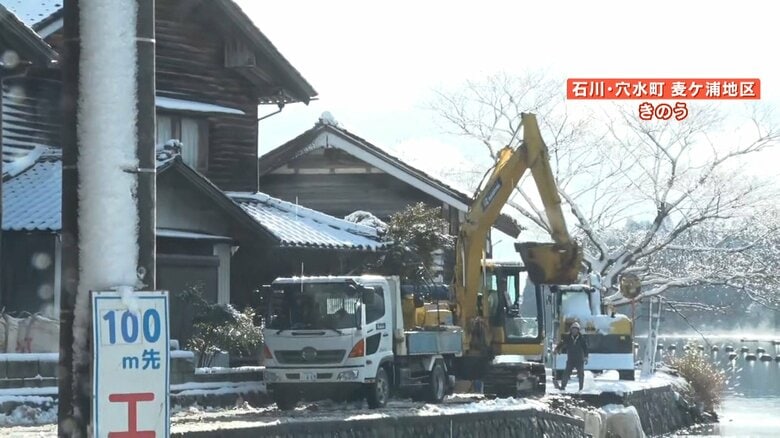 道の一部が崩れており、重機による復旧作業が行われている