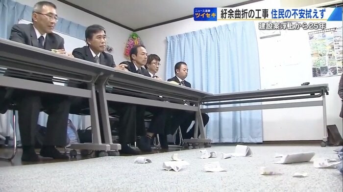 説明に不満を待った住民が破り捨てた資料が散らばる
