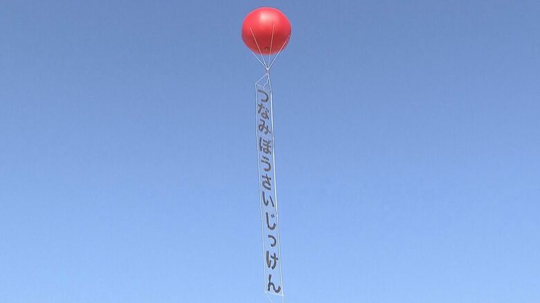 バルーンに吊るされた懸垂幕には「つなみぼうさいじっけん（津波防災実験）」と書かれている