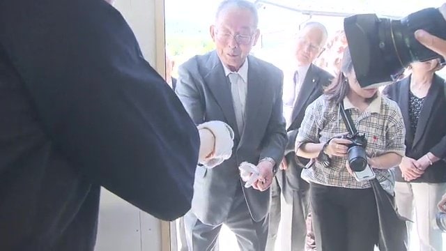 最初の作品を受け取る半谷秀辰理事長