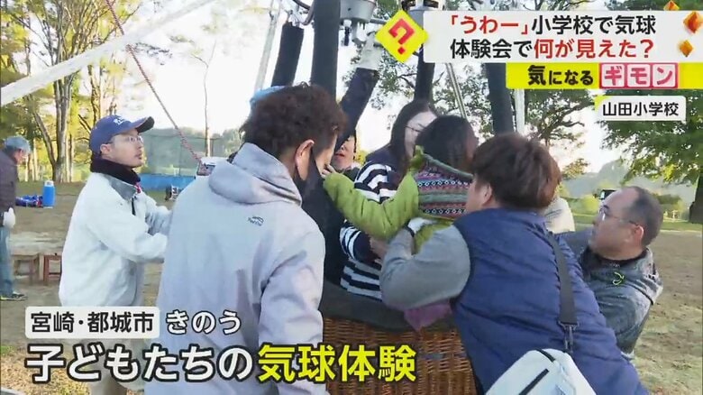 大人に抱き上げられ、気球に乗り込む子どもたち