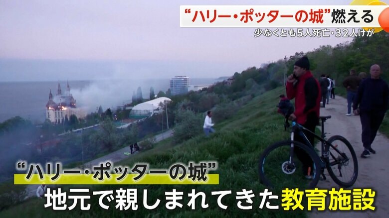 高台から海辺に立つ“ハリー・ポッターの城”が燃える様子を見る人の姿