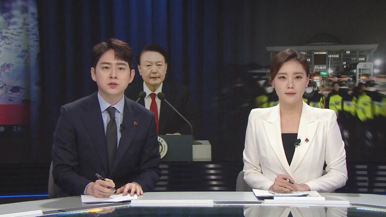 非常戒厳が宣言されたことを伝えるイ・アナウンサー（2014年12月4日・右）