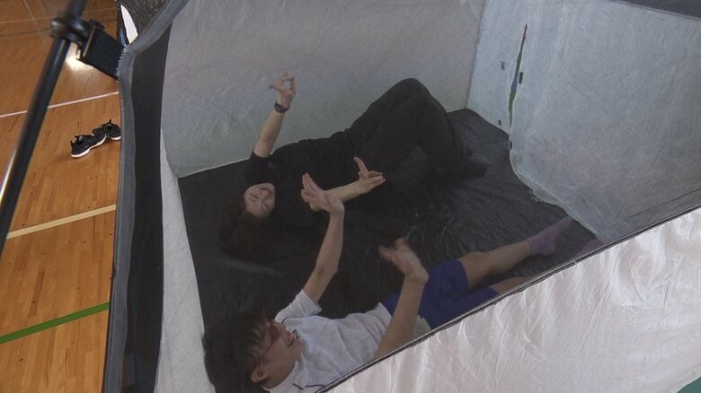 先生と一緒にテントでの寝心地を確認する児童（手前）