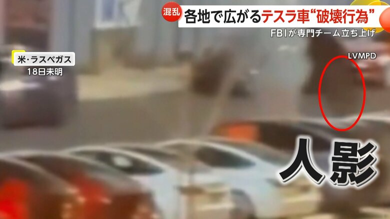 燃えている車に近づいていく黒い人影