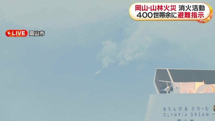 24日午前6時過ぎの現場の様子。山から白い煙が上がる。