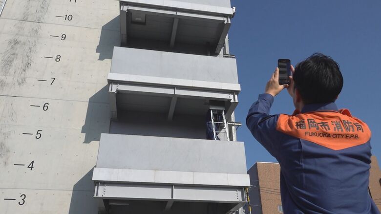 「避難用はしご」使用シーン撮影する坂口智浩さん