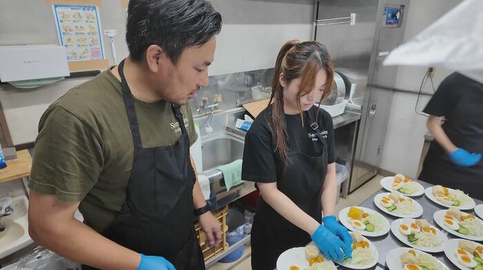 食事の準備をする鈴木さん（中央）と宿泊施設のオーナー・高橋さん