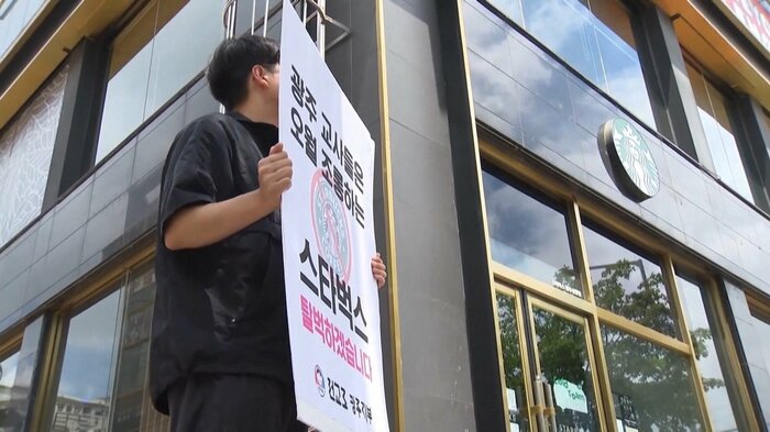 光州のスターバックス前で「スターバックスを非難する」と書かれたプラカードを掲げる抗議者（2026年5月22日）