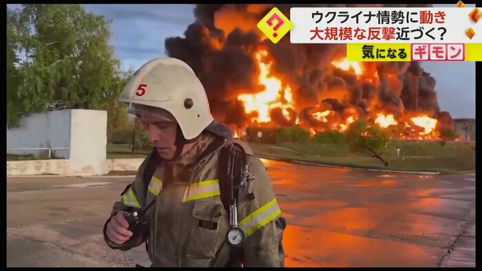 消防隊のすぐ後ろで炎が燃え上がっている