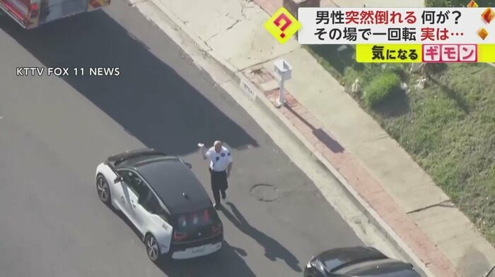 ロサンゼルス郊外の路上で、顔の辺りを手で仰ぐ男性