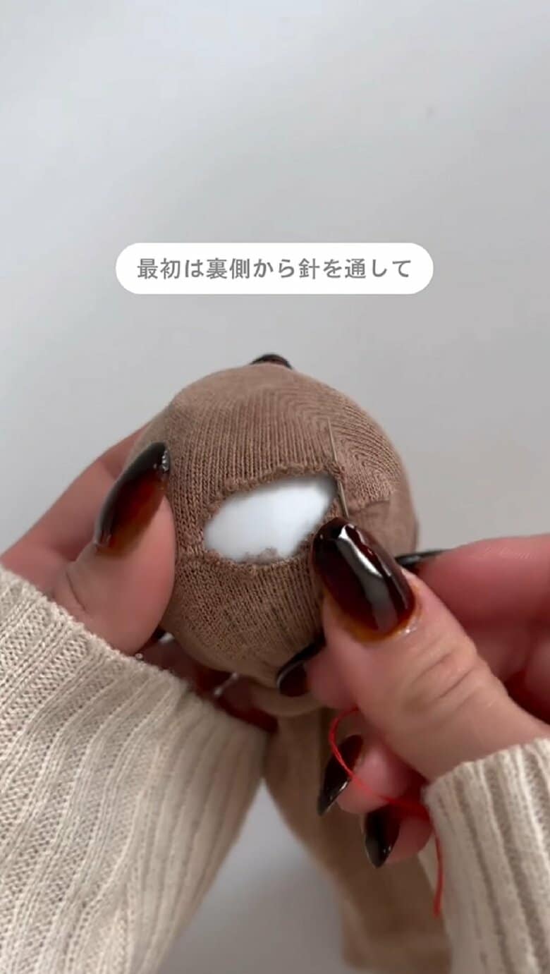 糸を通して玉結びをした針を、靴下の裏側から通す