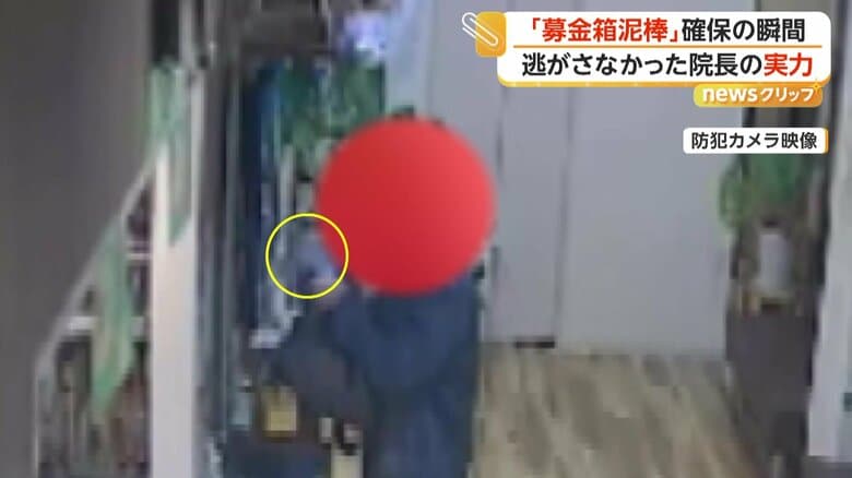 募金箱を手に取る男