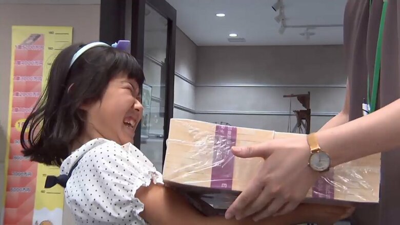 1億円の模造紙幣を持ち上げる子供