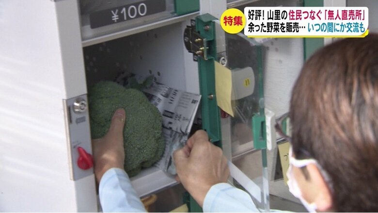 無人直売所のロッカーに野菜を入れる（長野・小谷村）