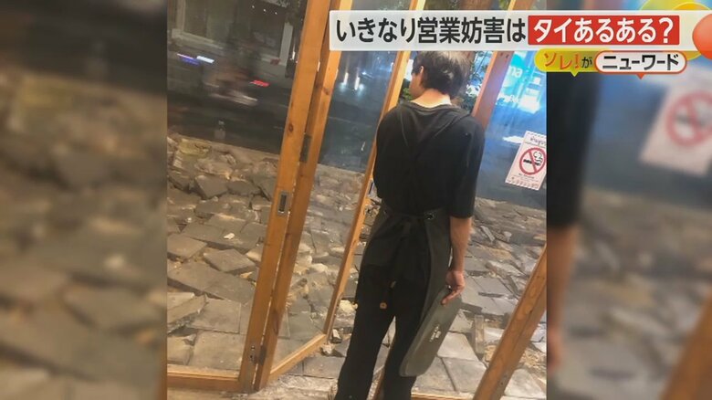 タイルが散乱した歩道を店内から覗きこむ従業員