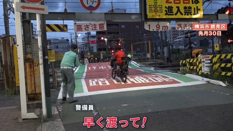 警報機が鳴る中、踏切に進入する自転車