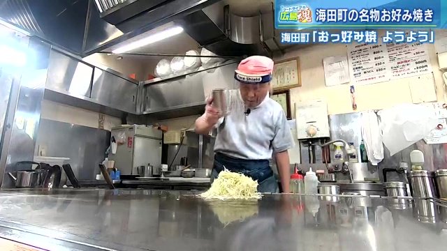 どっさりのキャベツに何かをかけている店主