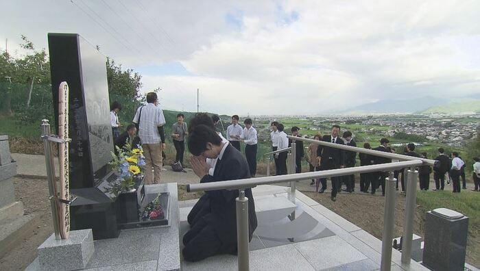 律希さんの墓に手を合わせる友人たち